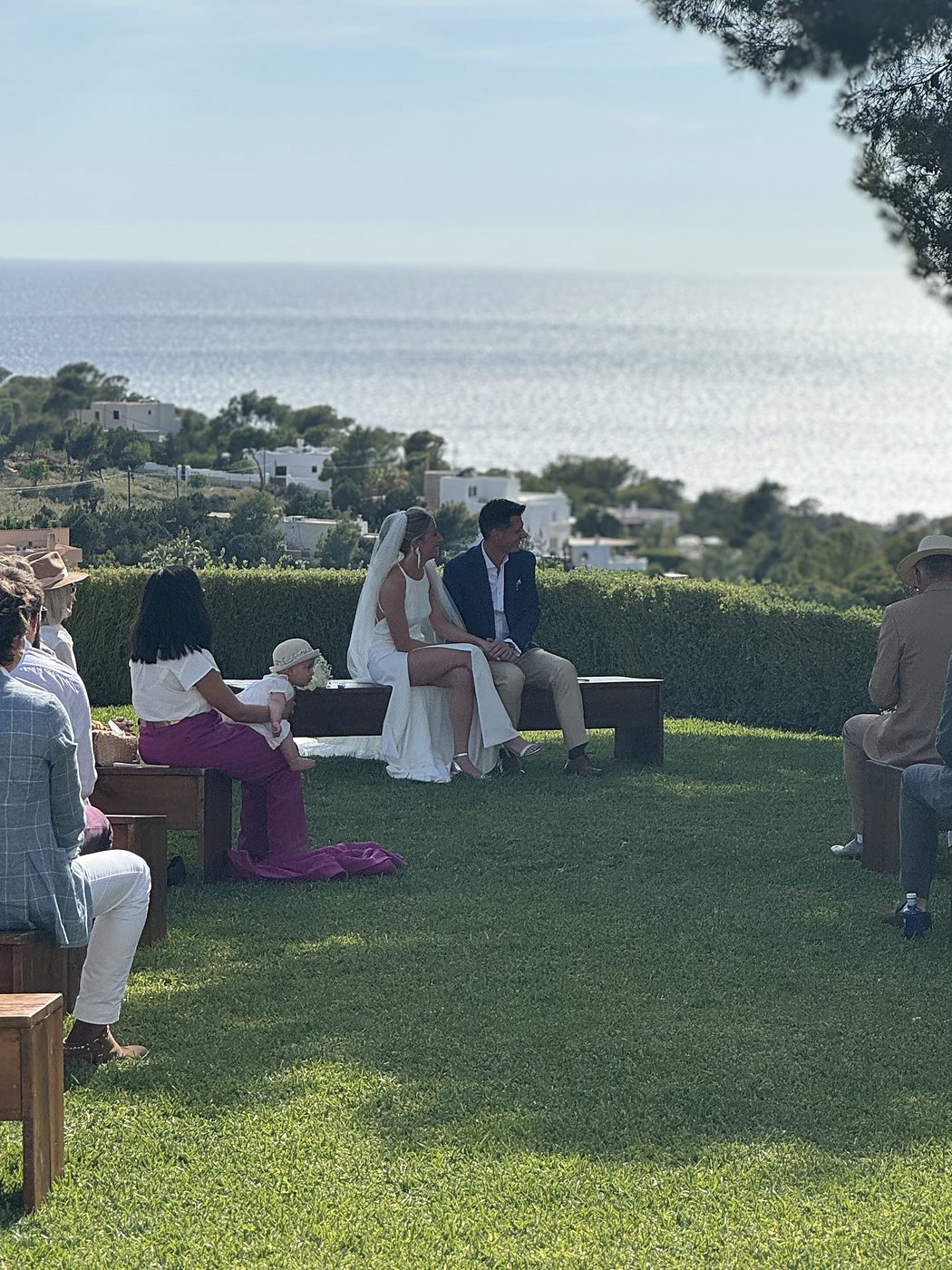 Cérémonie laïque de mariage en bord de mer à Ibiza, les mariés assis devant leurs invités