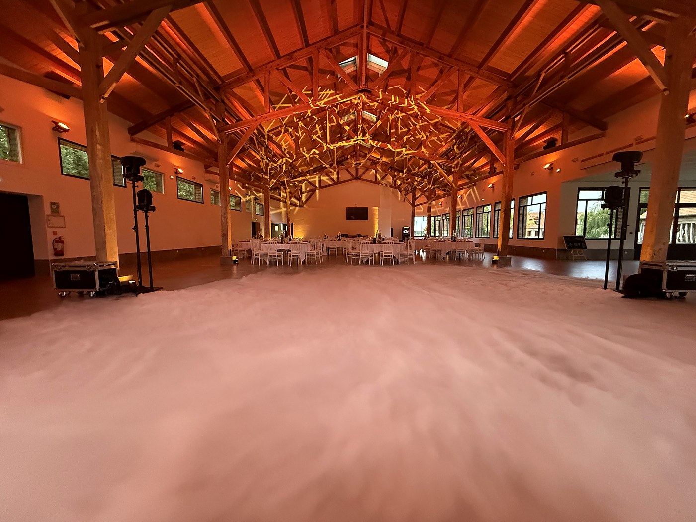 Salle de réception éclairée en ambre et fumée lourde sur la piste avant la soirée, mariage Pas-de-Calais