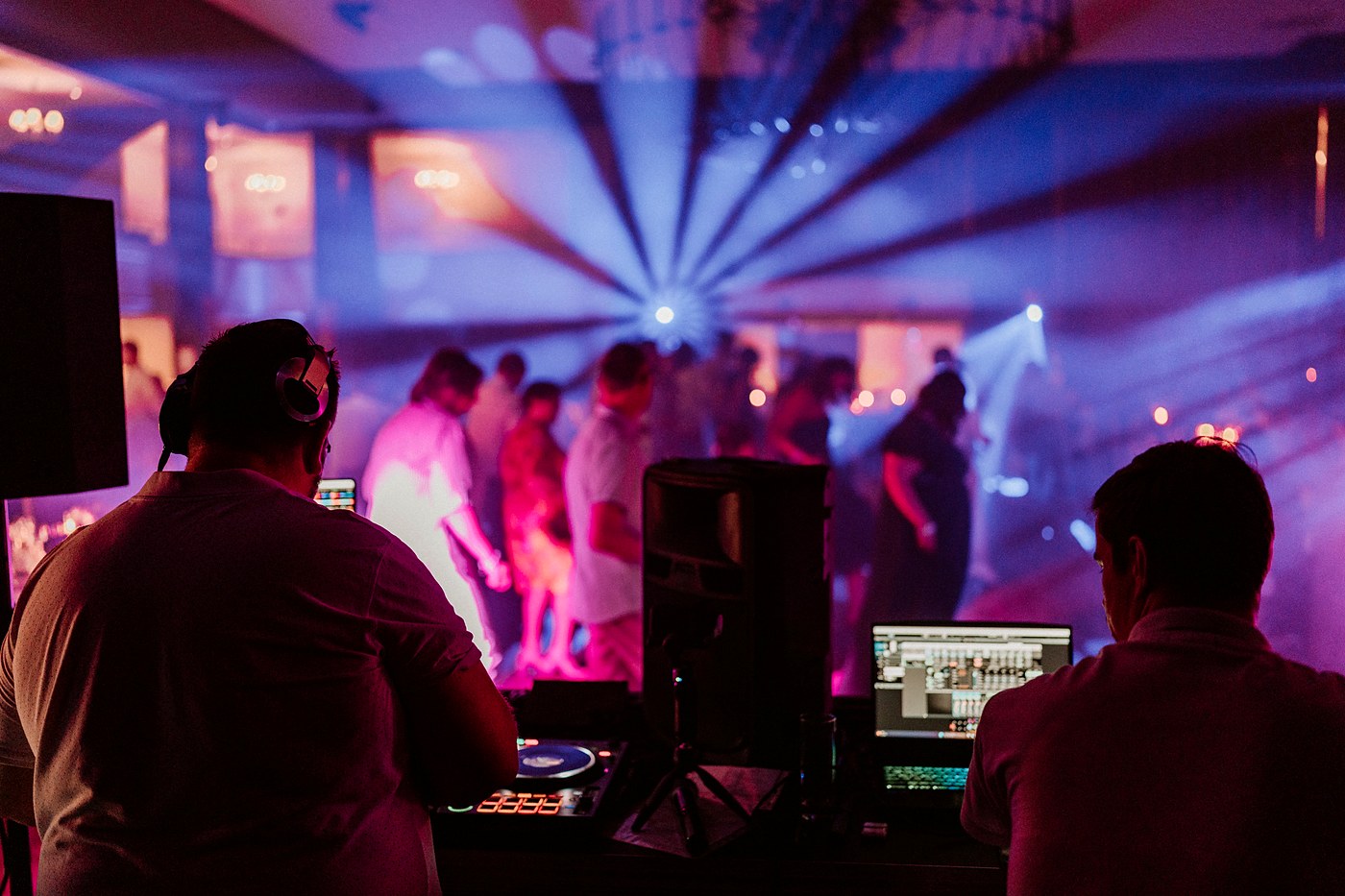 Régie de DJ de mariage avec ordinateur portable et contrôleur, face à une piste de danse remplie
