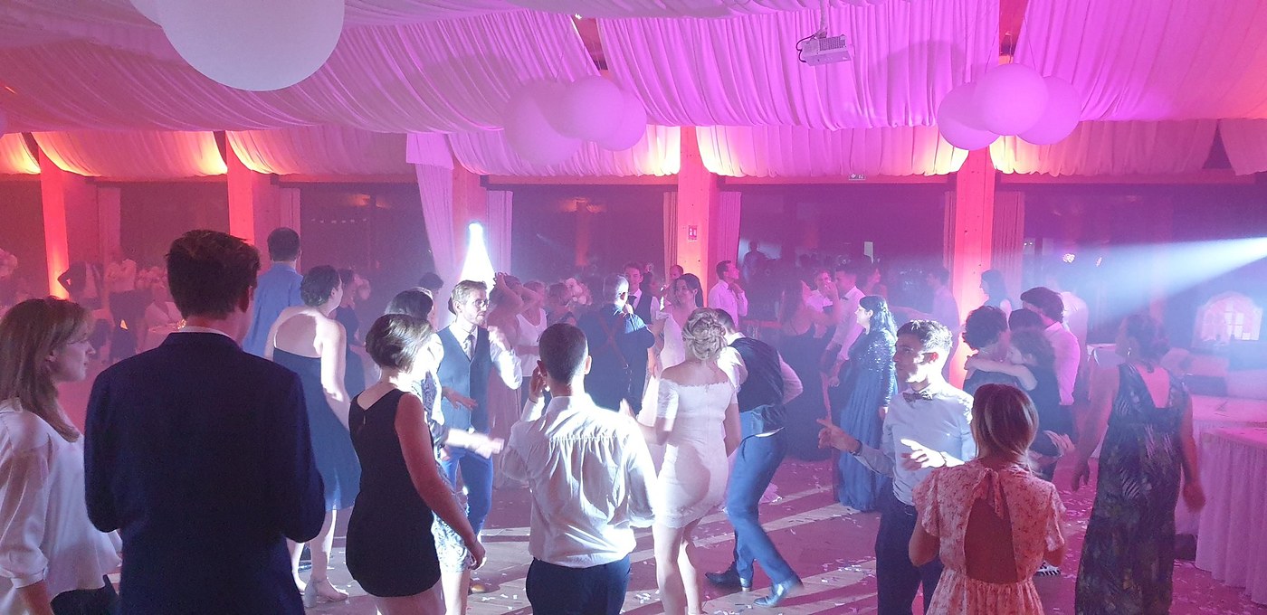 Piste de danse remplie d'invités sous un éclairage rose lors d'un mariage dans les Hauts-de-France