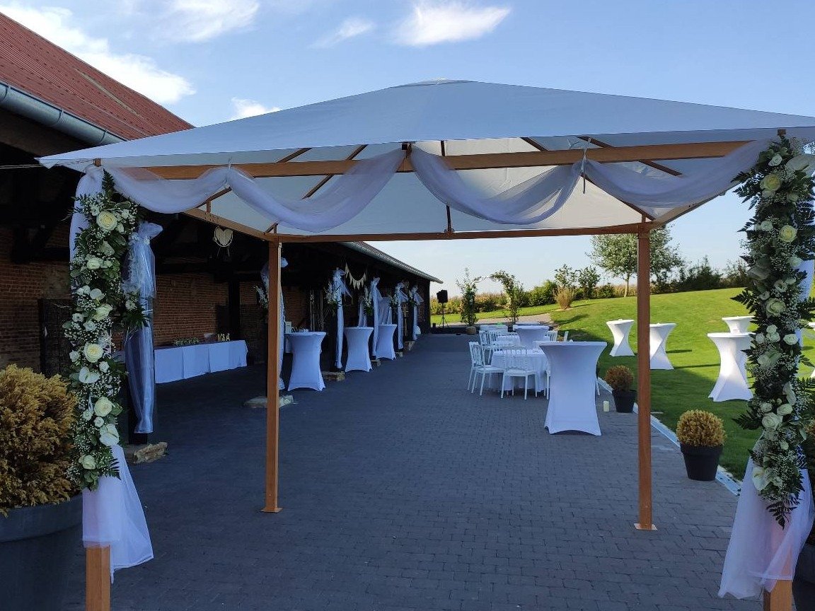 Espace de réception extérieur sous une pergola décorée lors d'un mariage dans le Nord