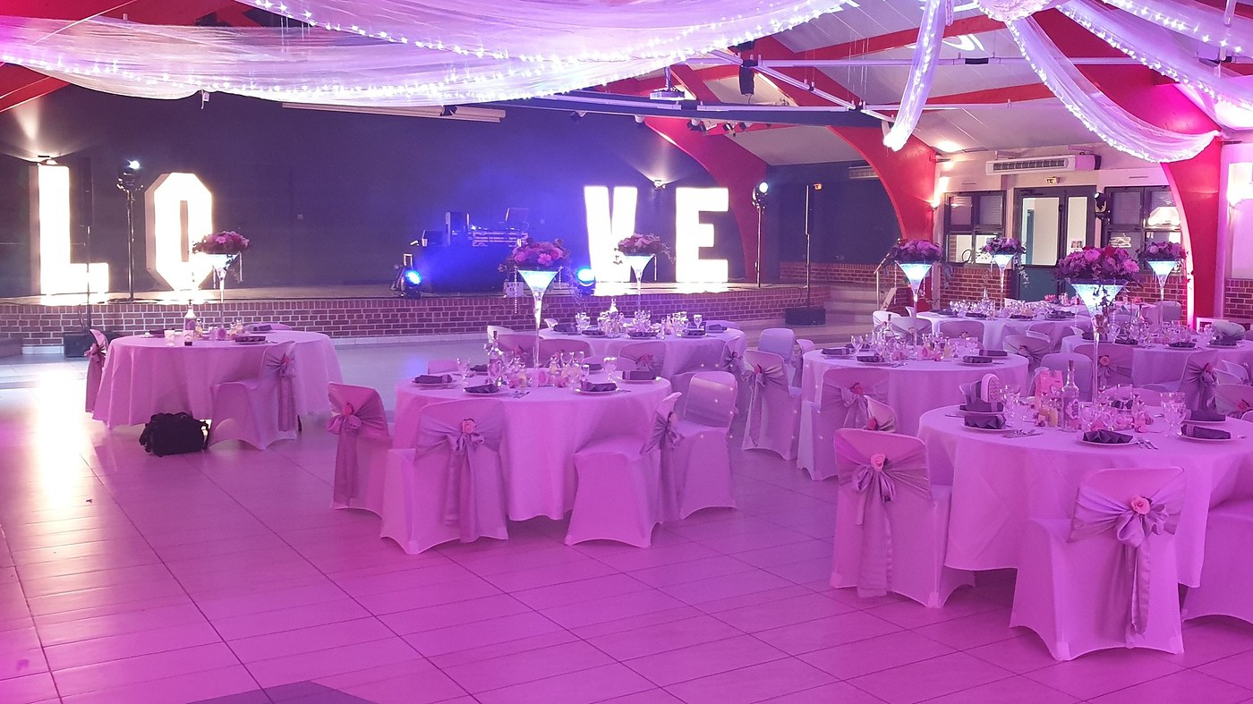 Salle de réception dressée pour un mariage, lettres LOVE lumineuses et éclairage rose dans le Nord