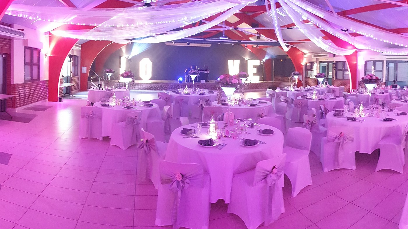 Tables dressées et éclairage rose dans une salle de réception de mariage du Nord Pas-de-Calais
