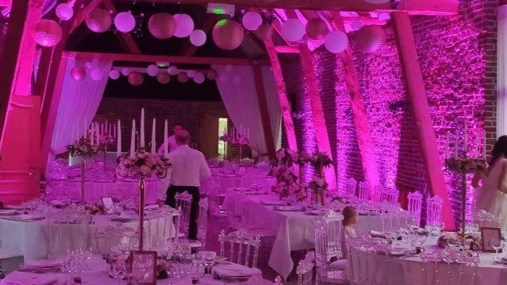 Tables dressées avec bougies sous un éclairage rose lors d'un mariage dans le Pas-de-Calais